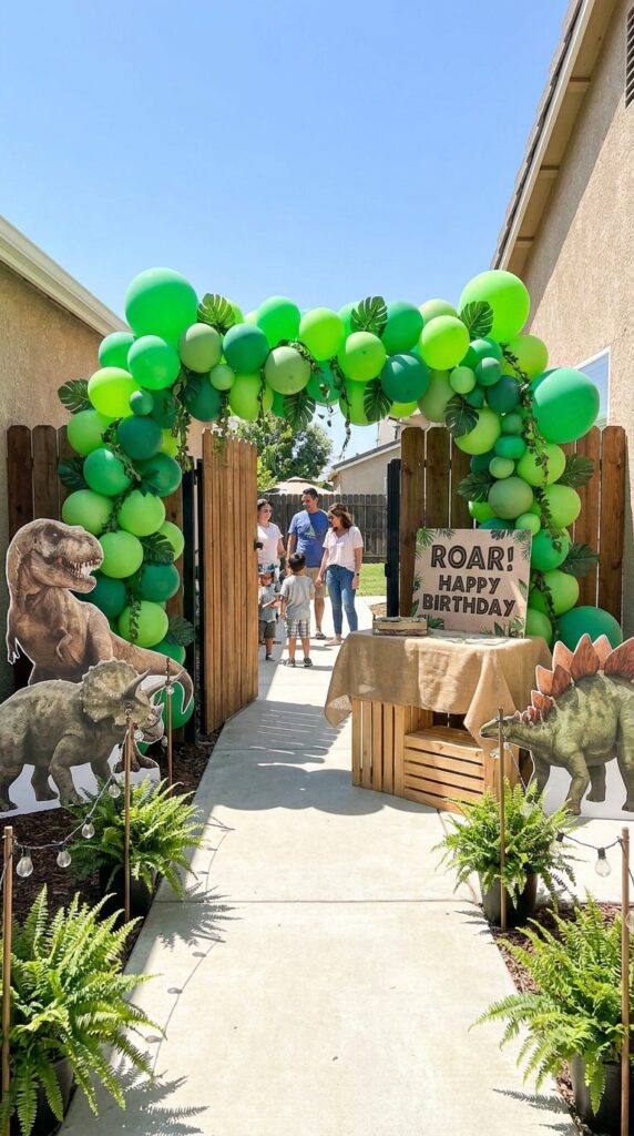 Dinosaur jungle themed birthday entrance with balloon arch and leaves
