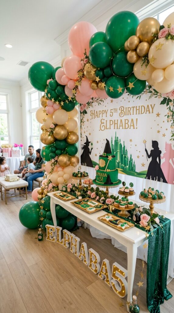 Emerald green and pink Wicked-inspired 5th birthday balloon party setup with magical decorations and dessert table.